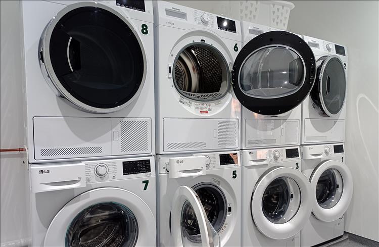 4 washing machines atop 4 driers in a plain room at Elan Oaks