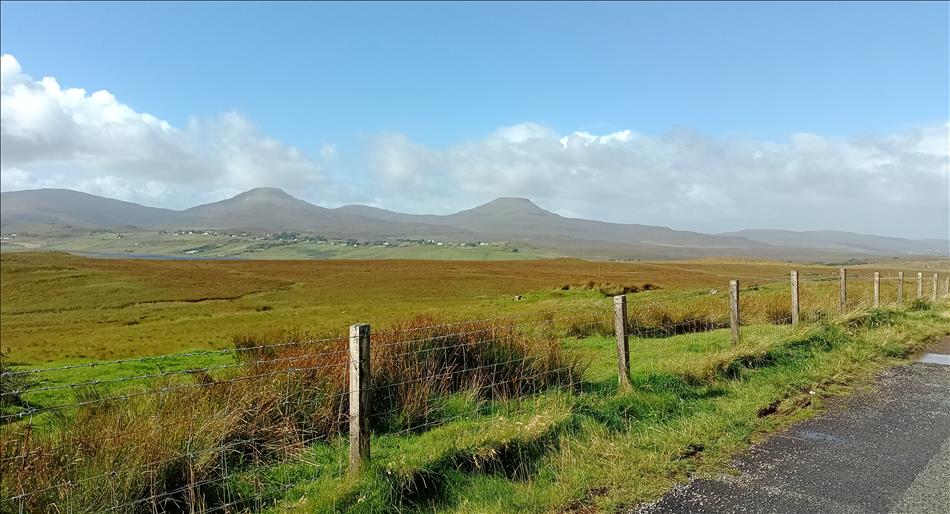 Vast open grasslands with mountains, a line of white houses in the far distance