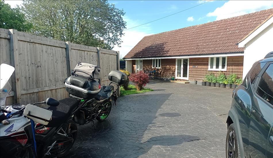 The bikes and a car, a private driveway and a bungalow with trees around