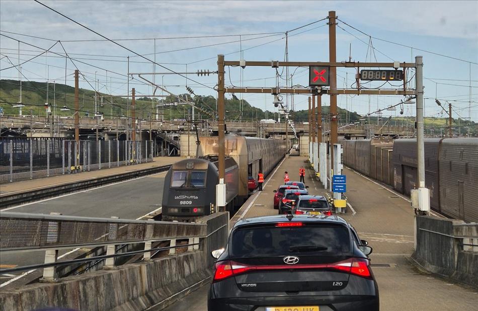 Big trains, a line of cars, lots of gantries and wires, concrete, poles and signs
