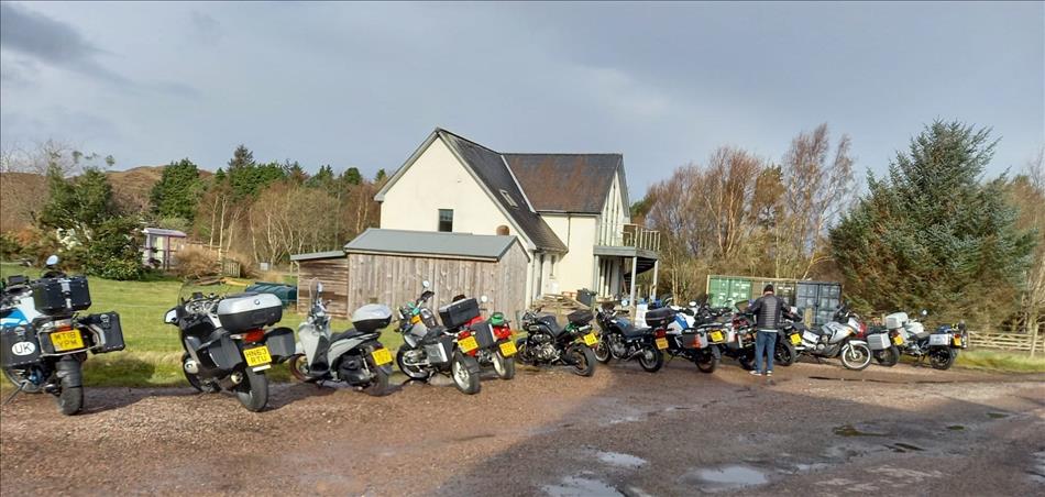 A row of motorcycles parked outside a small hotel in the rugged scenery of The Highlands
