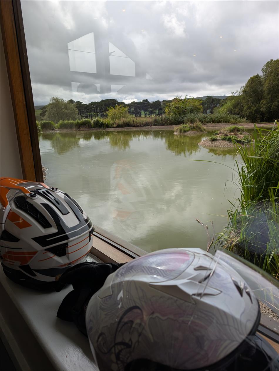 Looking though a glass window over a pond with the Lake District scenery in the distance.