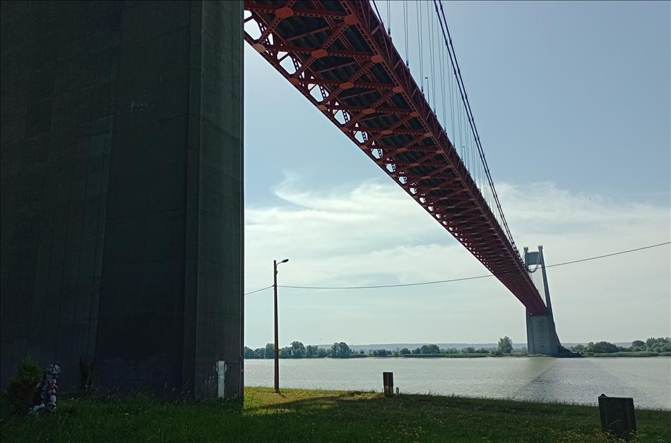 Looking up we see huge concrete towers and the metal trellis of the underside of a huge bridge
