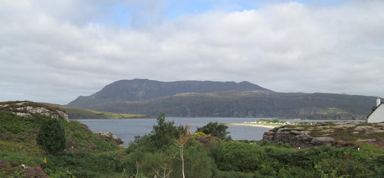 A massive block of a mountain dominates the skyline while a little village pokes out below