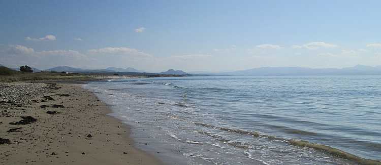 long broad beach with the welsh highlands in the hazy distance