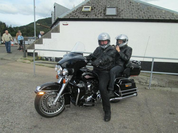 a couple on board a large big black harley davidson motorcycle at inverary