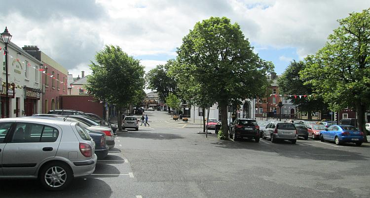 Kildare town centre with an open feel, trees and shops in the sun