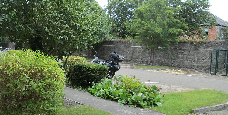 Ren's 125 nestles behind bushes in the car park, ready to ride into Ireland