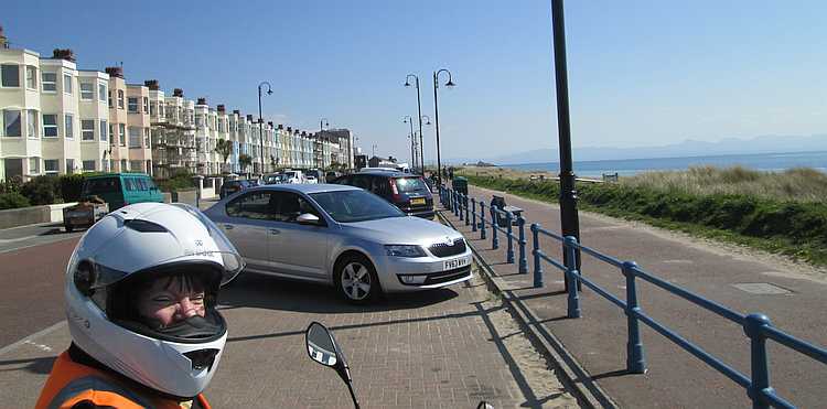 Pwhelli beach front with a row of tall houses and the gf smiling in her helmet