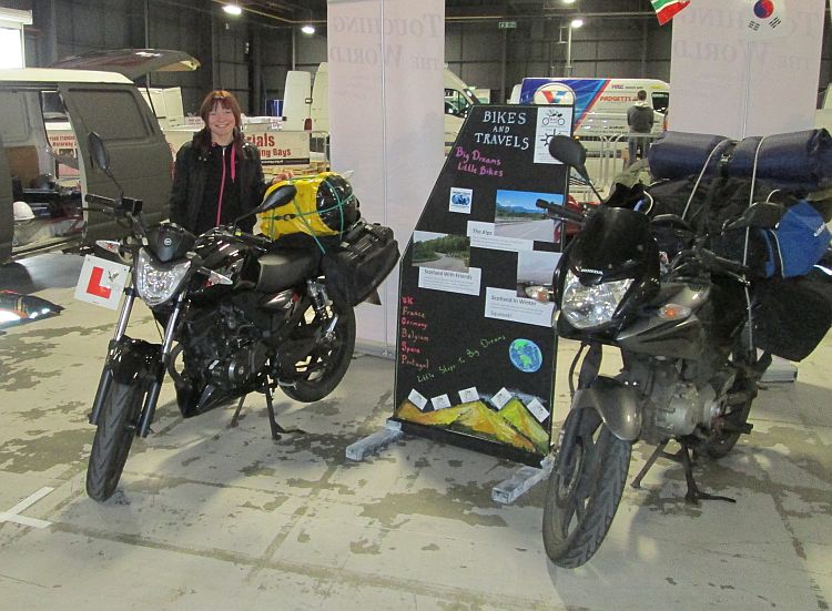 Sharon stands next to our bikes and our board at the manchester bike show