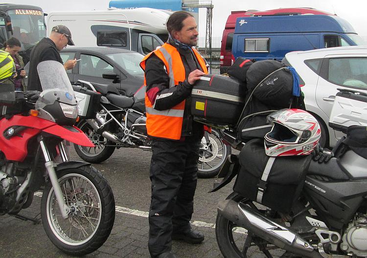 Ren stands next to his bike in his waterproof overpants and bike gear