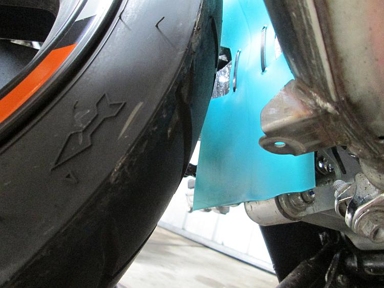 The linkage is just visible behind the green plastic of the hugger