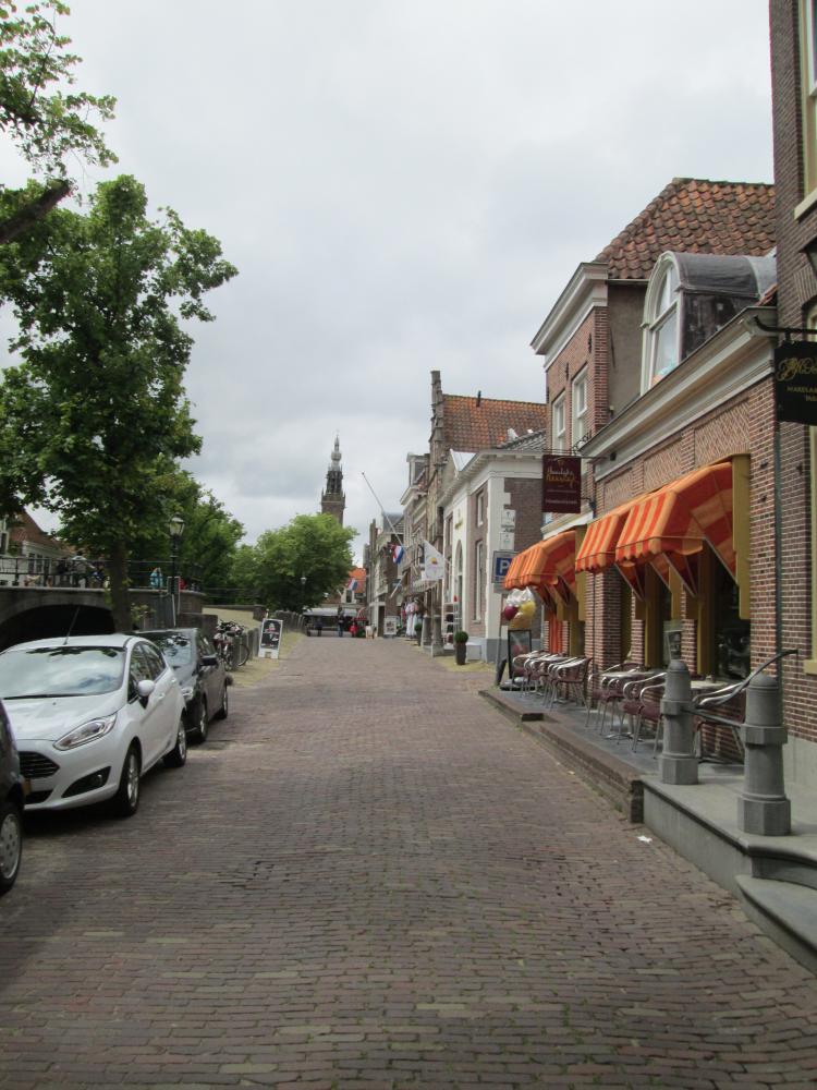 A typical Dutch street, canal, block paved roads, shops, cafes and trees