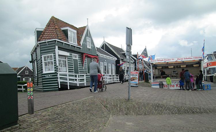 An old wooden dutch house next to a hot dog van in marken