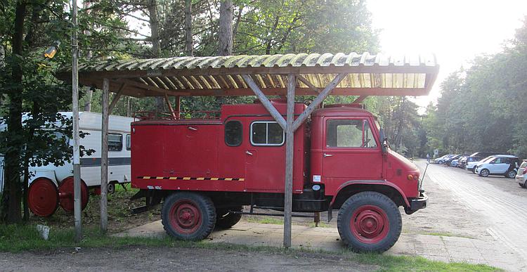 An old Unimog fire truck under a wooden canpoy