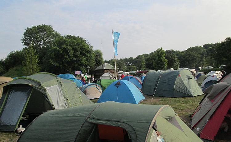 Lots of tents squashed into a small dusty patch of land at caming zeeburg in amsterdam