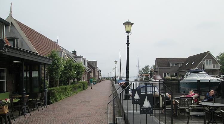A narrow lane with block paving and houses runs next to a canal in Holland