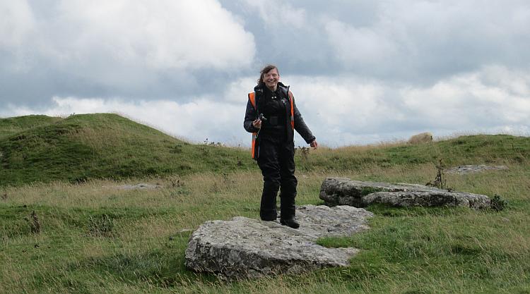 Sharon smilling in the wind standing on a fallen stone at Arbor Low
