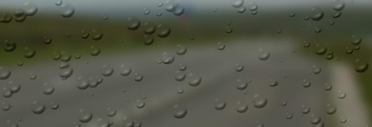 A very blurred stretch of road with rain drops over the whole image
