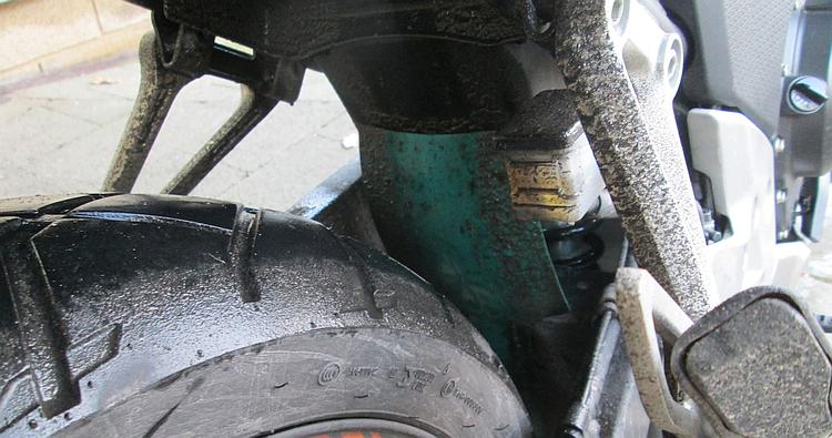 The rear wheel and wheel arch of Ren's CB500X covered in a thick layer of black road salt