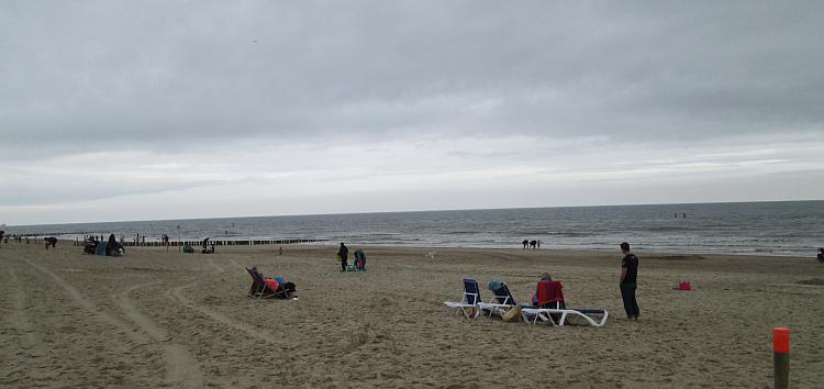A sandy beach with a sprinking of holiday makers, but the skies are grey