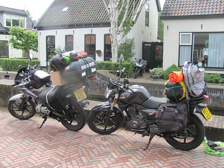 The 2 overladen 125 motorcycles with luggage beside the canal on the way to Amsterdam
