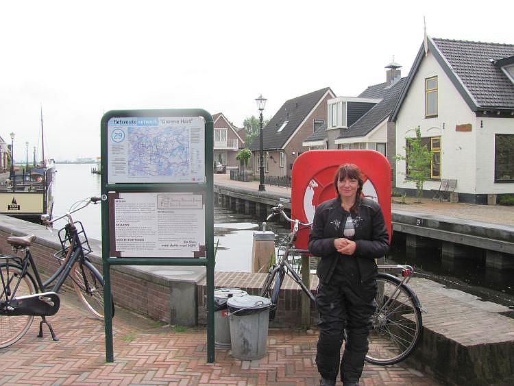 Sharon stands in front of an information sign wringing her hands and trying to smile