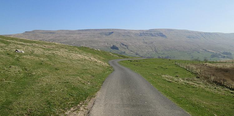 A single track tarmac lane winds though the hills and valleys of the Yorkshire Dales