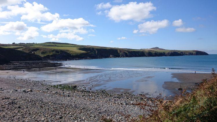 A broad sunkissed beach between rocky outcrops at Abereiddy