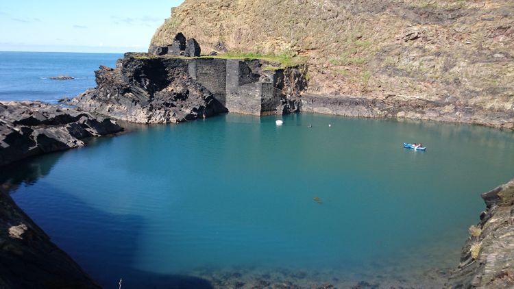 Steep slate mine walls lead into a deep turquoise pool at The Blue Lagoon