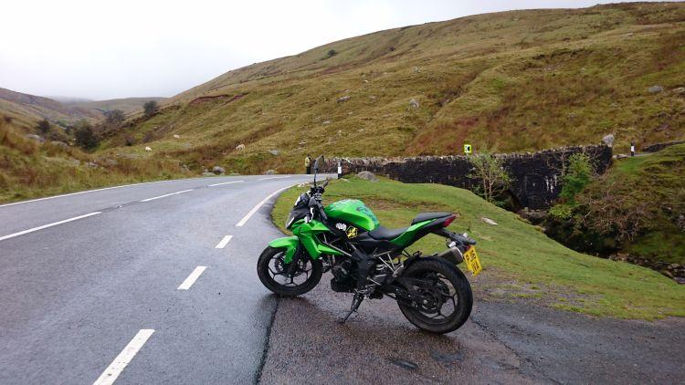 Sharon Kawasaki in a rugged rural landscape with Ren in the distance behind a wall