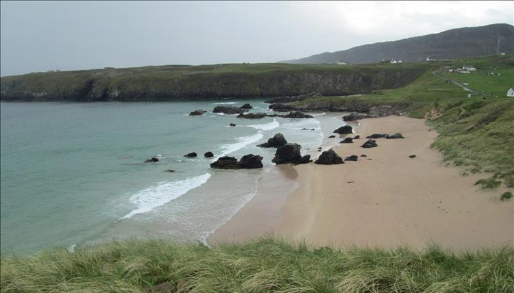 A hoseshoe shaped cove with a sandy beach in the centre, surrounded by rocky cliffs