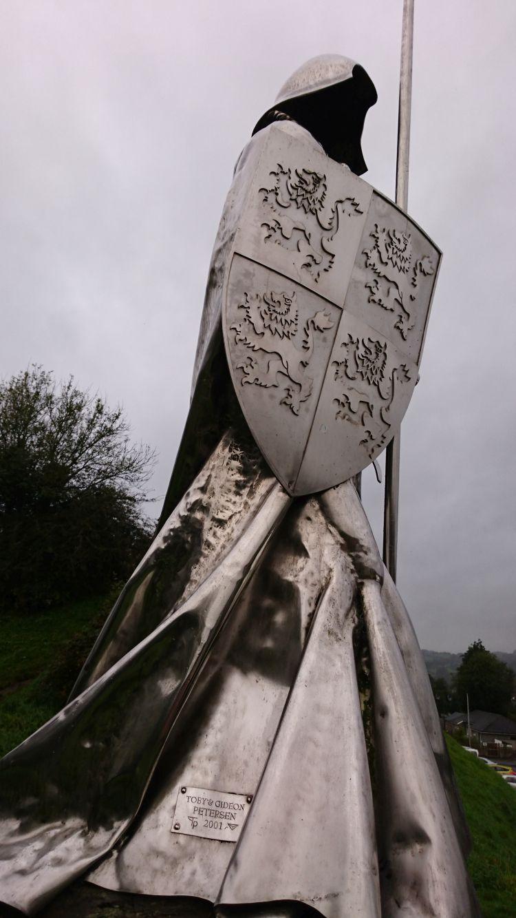 The same statue from the side, massive shiny steel robe and sheild and helmet