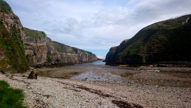Looking out from Smoo Cave we see a steep sided cove with a river running out to the sea