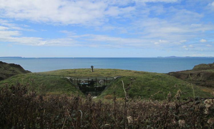 What looks like a coastal field has a cutout within which the glass windows lead to modern home