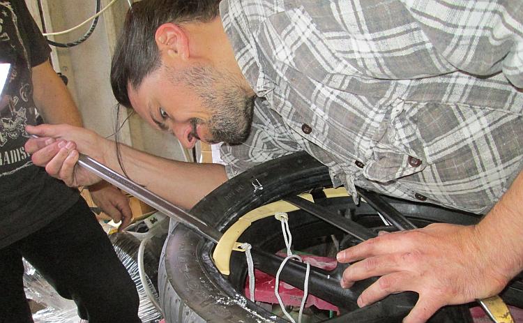Ren looks intensely at the tyre that he's trying to remove from a rim
