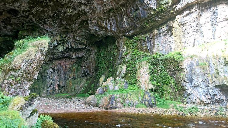 Inside Smoo Cave the craggy stone walls and ceiling tower over the viewer