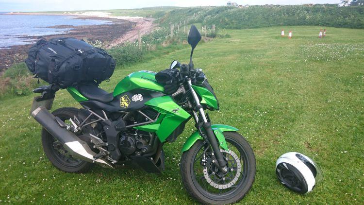 Sharon's Kawasaki Z250SL at the campsite overlooking a stony and windswept beach