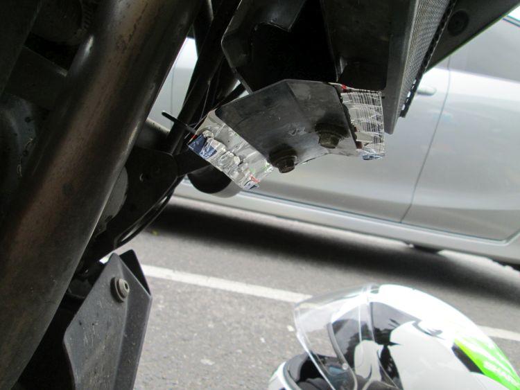 A squashed beer can is bolted on with the original small cover at the entrance to the radiator cowl