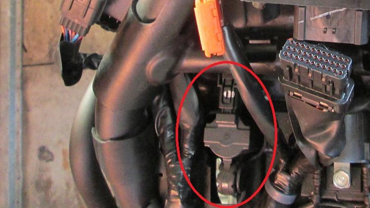 A small plastic piece of equipment between many other items under the tank