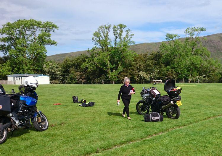 A lady walks with hands full of camping kit to fill her top box with at Applecross