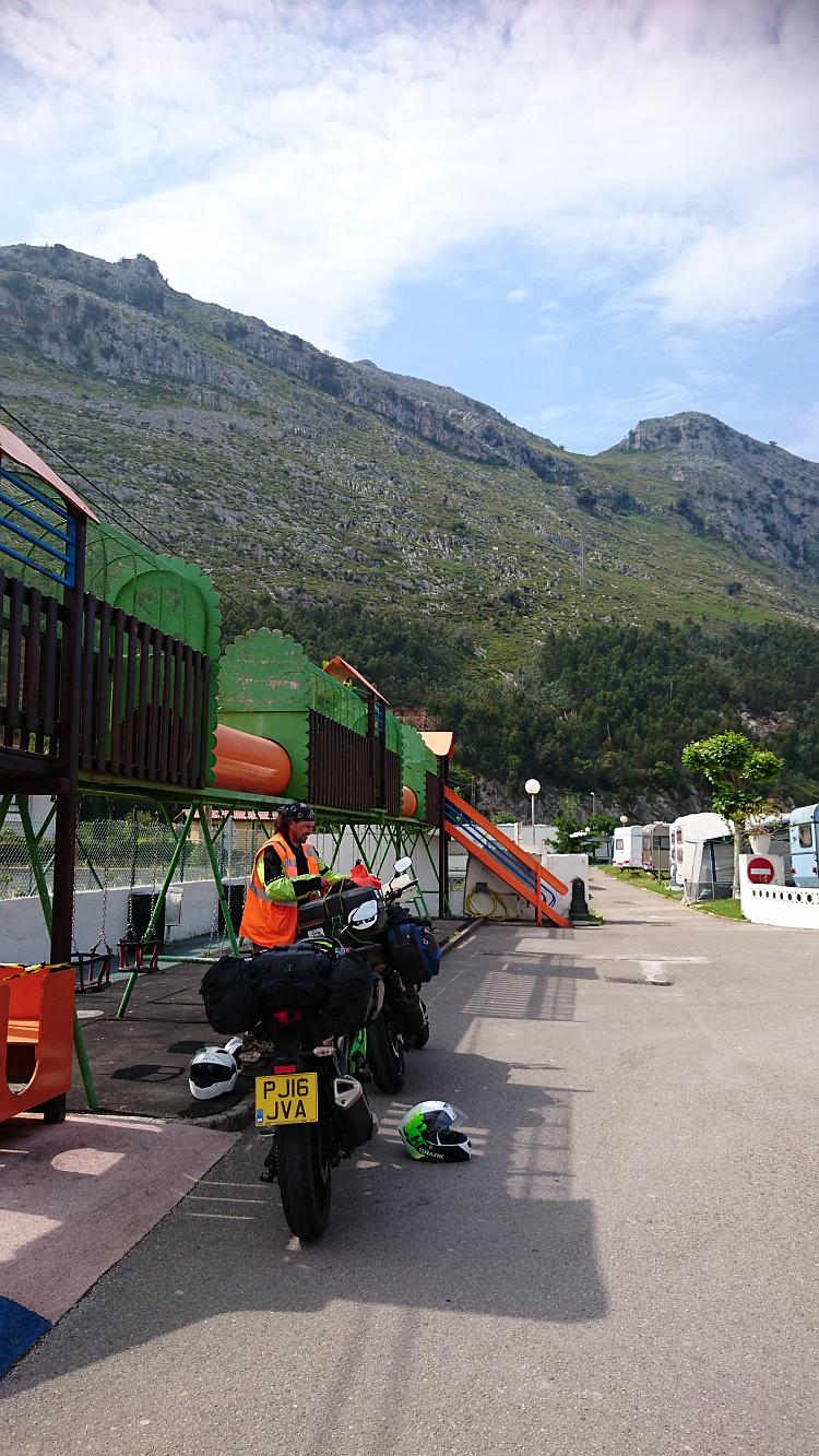 Ren ponders something on his bike with the Spanish hills behind him at the campsite