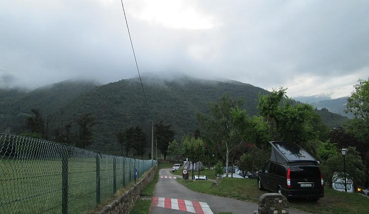 Looking over the campsite across tents and vans the hills are covered in a thick layer of cloud