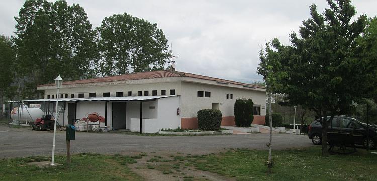 A large low white pained building under the grey skies