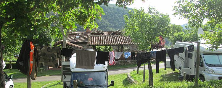 Clothes on a line amidst trees and campervans at the campsite in Potes