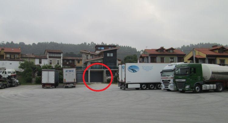 The garage under a house, circled in red, on a large vast area with lorries on it