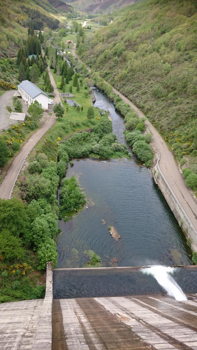 We're looking down the steep side of a concrete dam and out to a beautiful green valley
