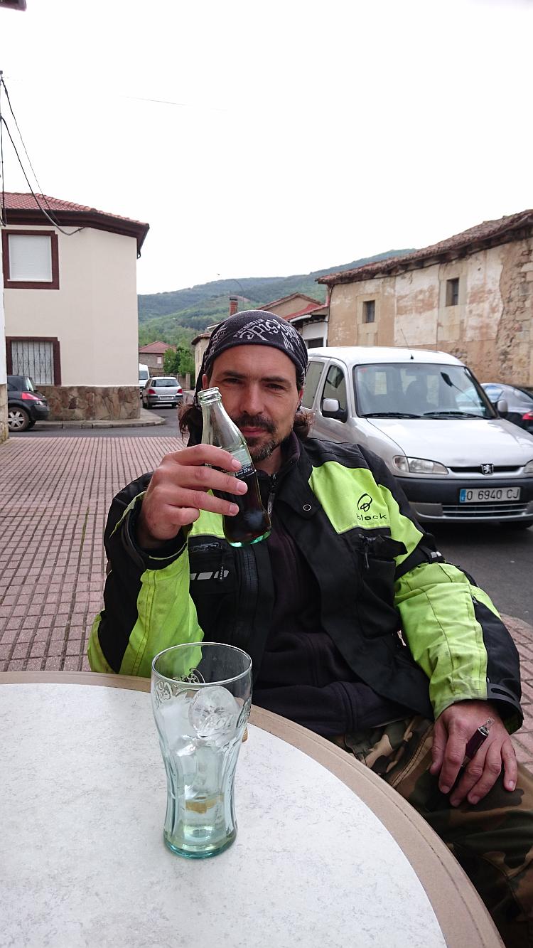 Ren smiles and tips a bottle of pop as a toast while sitting outside the bar in the town