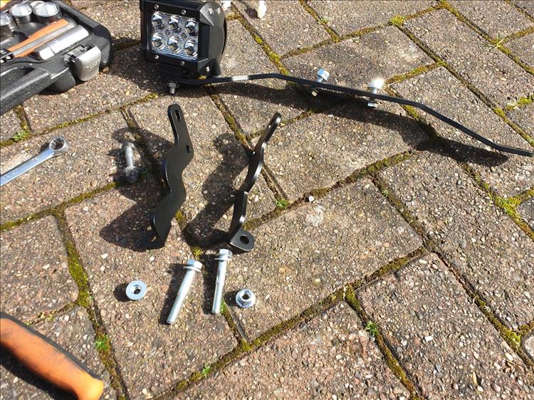 The mounting kit, fog lights, tools and fixing spread all around the floor