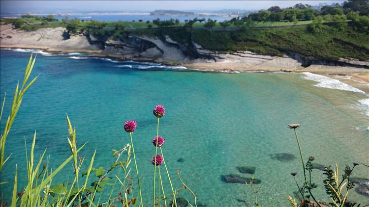 A rocky cove with turquoise sea leads to a sandy beach just north of Santander